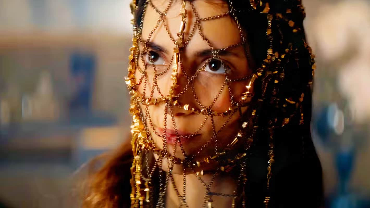 a-woman-wears-a-red-gown-with-gold-chains-over-her-face-in-dune-prophecy