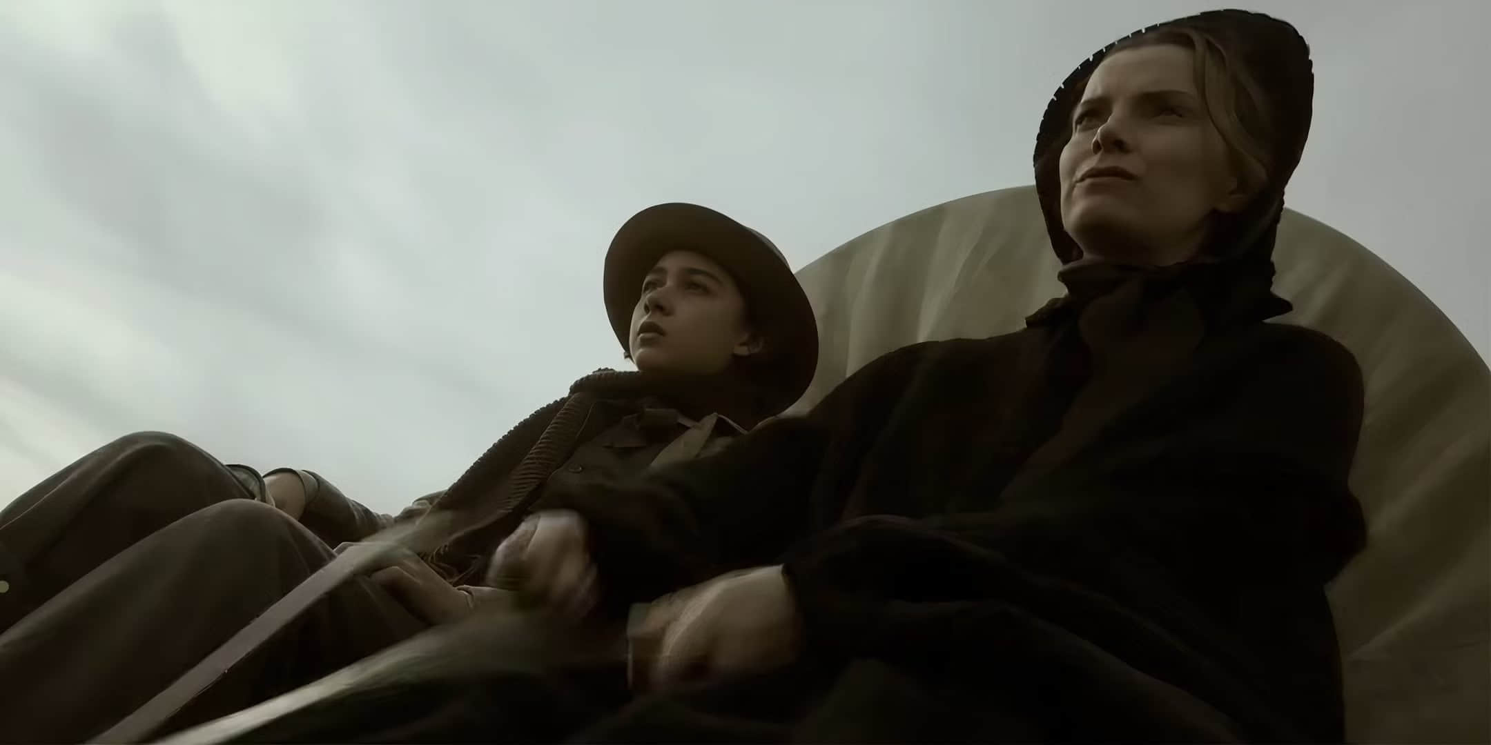 betty-gilpin-s-sara-looking-determined-and-prestin-mota-s-devin-looking-uncertain-while-driving-a-wagon-in-american-primeval