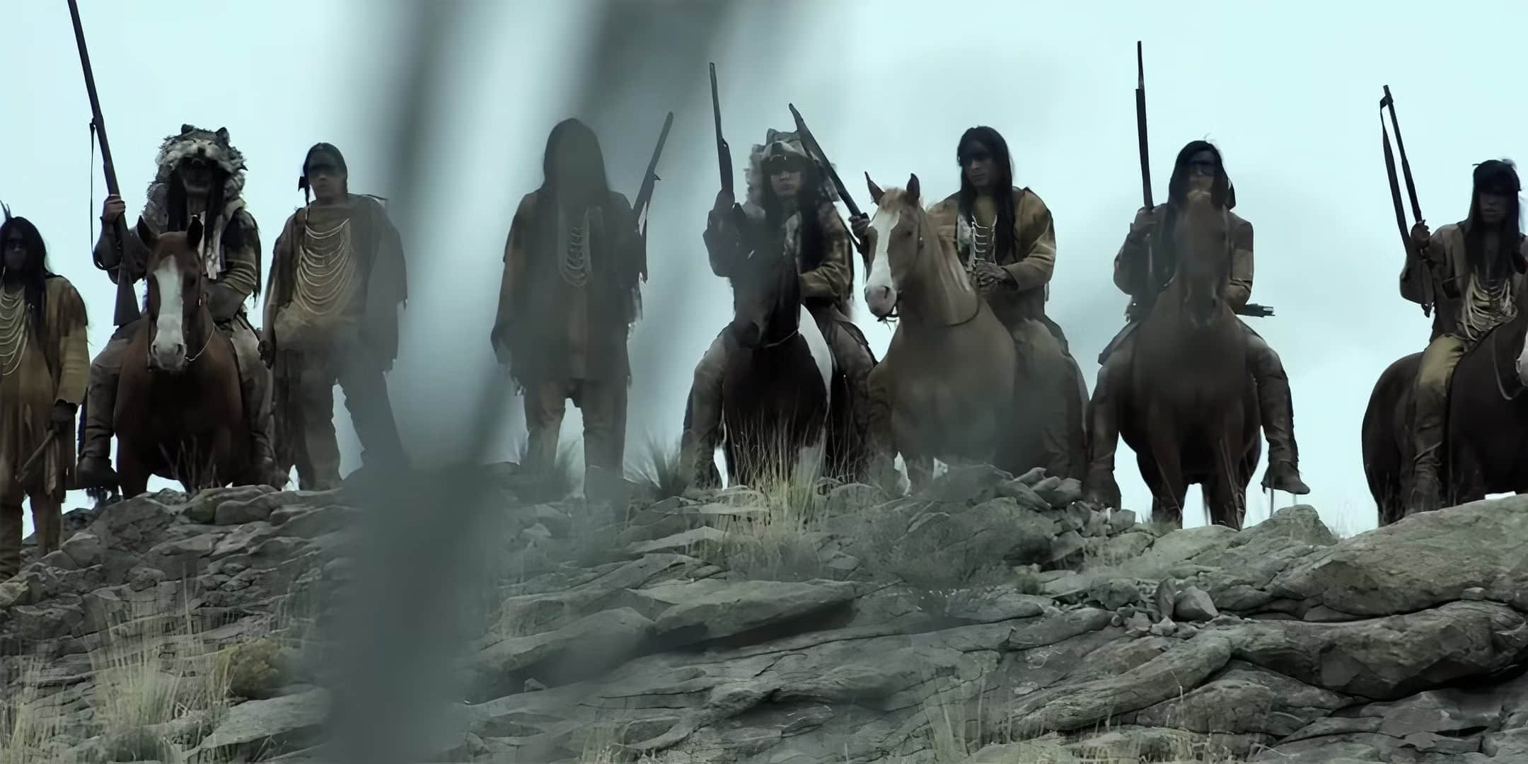 a-group-of-native-americans-standing-on-a-hillside-looking-battle-ready-in-american-primeval