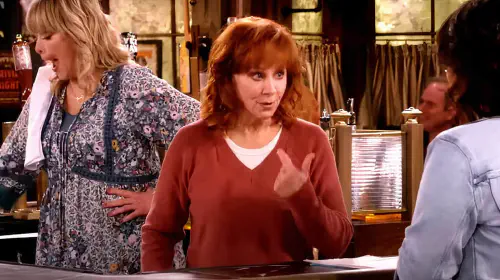 assets/reba-points-the-finger-at-herself-while-at-the-bar-in-happy-s-place.jpeg