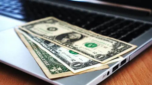 assets/Laptop-with-black-screen-and-three-dollar-bills-laid-out-on-keyboard.jpeg