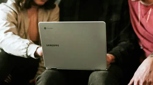 assets/Samsung-Chromebook-in-lap-of-user-being-shared-with-two-friends-1.jpeg