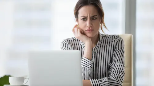 assets/Woman-at-desk-frowning-at-her-white-laptop-1.jpeg
