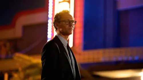 assets/tom-hiddleston-with-a-neon-sign-in-the-back-in-the-life-of-chuck.jpeg