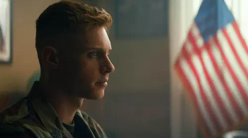 assets/max-parker-s-sullivan-looking-intensely-while-sitting-in-an-office-with-an-american-flag-in-the-background-in-boots.jpeg