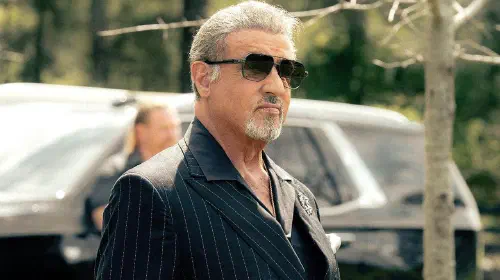 assets/sylvester-stallone-s-dwight-standing-with-a-cigar-in-his-hand-in-tulsa-king-season-3-yt.jpeg