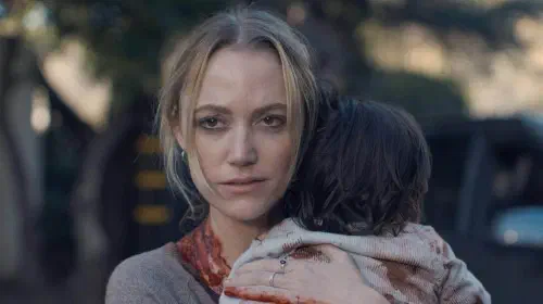 assets/maika-monroe-in-the-hand-that-rocks-the-cradle-holding-a-baby-with-blood-on-her-hand-and-necck.jpeg