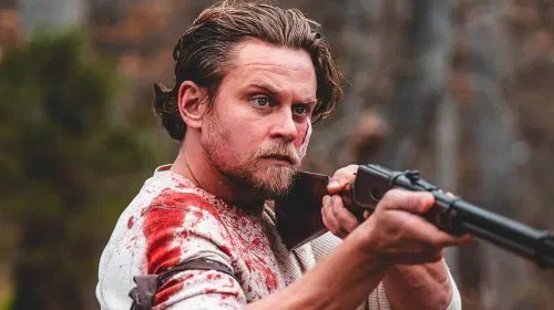 assets/billy-magnussen-holding-rifle-in-violent-ends.jpeg