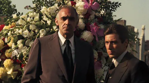 assets/tessio-and-michael-standing-next-to-flowers-in-the-godfather.jpeg