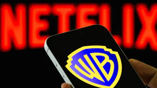 assets/warner-bros-logo-on-phone-with-netflix-logo-blurred-in-background-1.jpeg