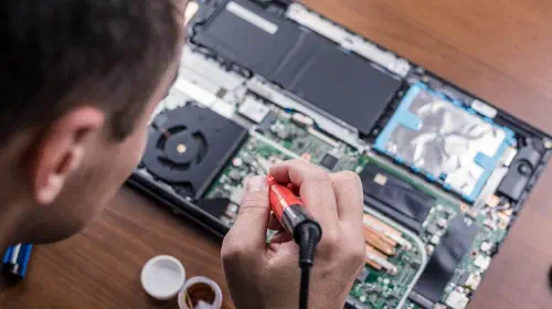 assets/Man-soldering-an-open-laptop-with-internal-components-exposed.jpeg
