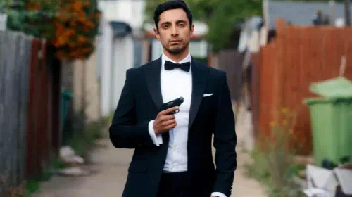 assets/riz-ahmed-dressed-in-tux-with-a-gun-pose-in-bait.jpeg