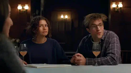 assets/zendaya-and-robert-pattinson-reaching-to-the-game-in-the-drama.jpeg