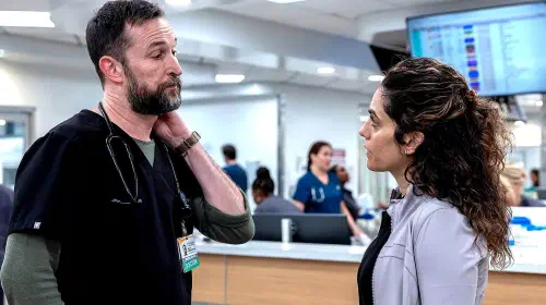 assets/noah-wyle-s-dr-robby-rubbing-the-back-of-his-neck-while-talking-to-sepideh-moafi-s-dr-al-hashimi-in-the-pitt-season-2.jpeg