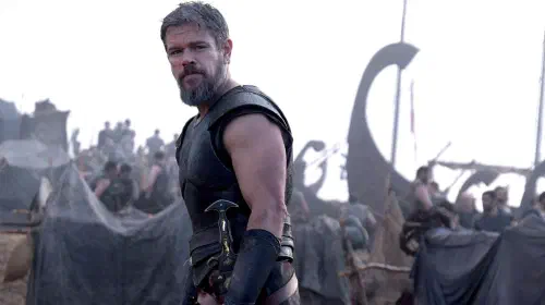 assets/matt-damon-as-odysseus-looking-off-the-left-with-a-ship-and-crew-behind-him-in-the-odyssey.jpeg