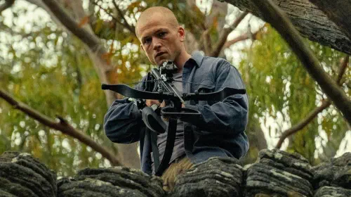 assets/taron-egerton-holding-a-crossbow-in-apex.jpeg