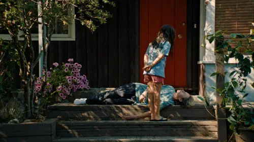 assets/sasha-bent-over-jeremy-as-he-plays-dead-on-the-front-steps-in-blue-heron.jpeg