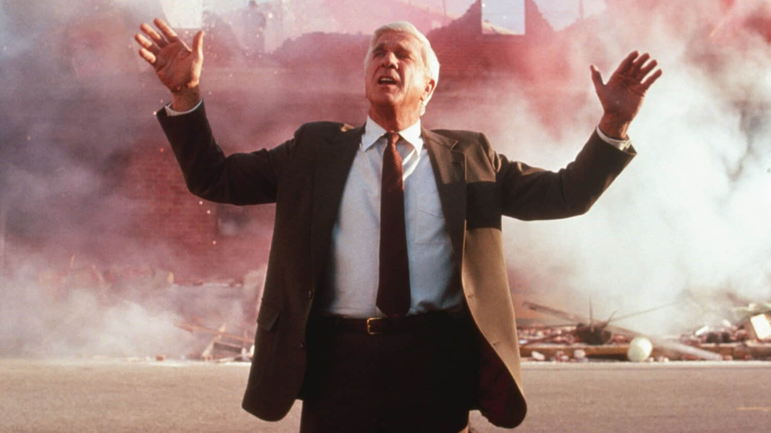 leslie-nielsen-s-frank-standing-in-front-of-an-explosion-with-his-hands-up-in-the-naked-gun.jpeg