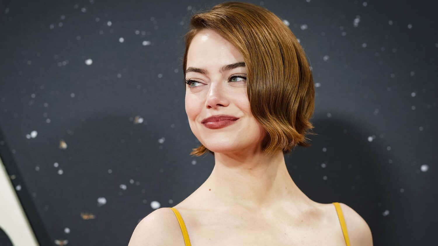 emma-stone-smiling-over-her-shoulder-at-a-red-carpet-event.jpeg