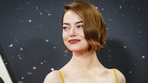 assets/emma-stone-smiling-over-her-shoulder-at-a-red-carpet-event.jpeg