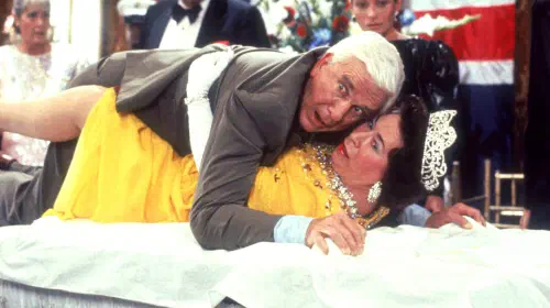 assets/leslie-nielsen-s-frank-looking-shocked-while-laying-on-top-of-jeanette-charles-queen-elizabeth-ii-in-the-naked-gun.jpeg