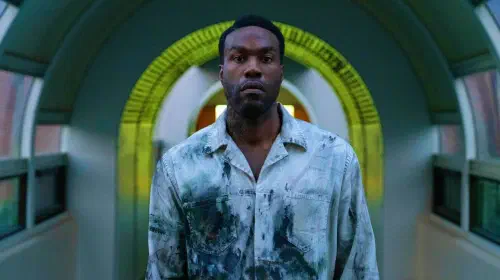 assets/yahya-abdul-mateen-ii-as-anthony-looking-intense-underneath-a-yellow-arch-in-candyman-2021.jpeg