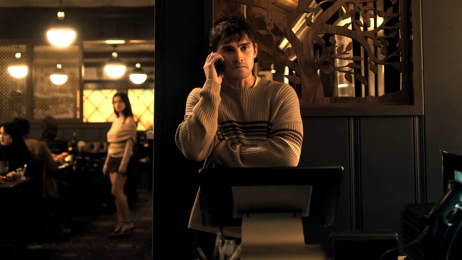 michael-johnston-s-bear-looking-worried-on-the-phone-with-inde-navarrette-s-nikki-standing-creepily-in-the-background-of-the-restaurant-in-obsession.jpeg