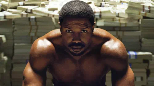 assets/creed-3-michael-b-jordan-in-front-of-pile-of-money.jpeg