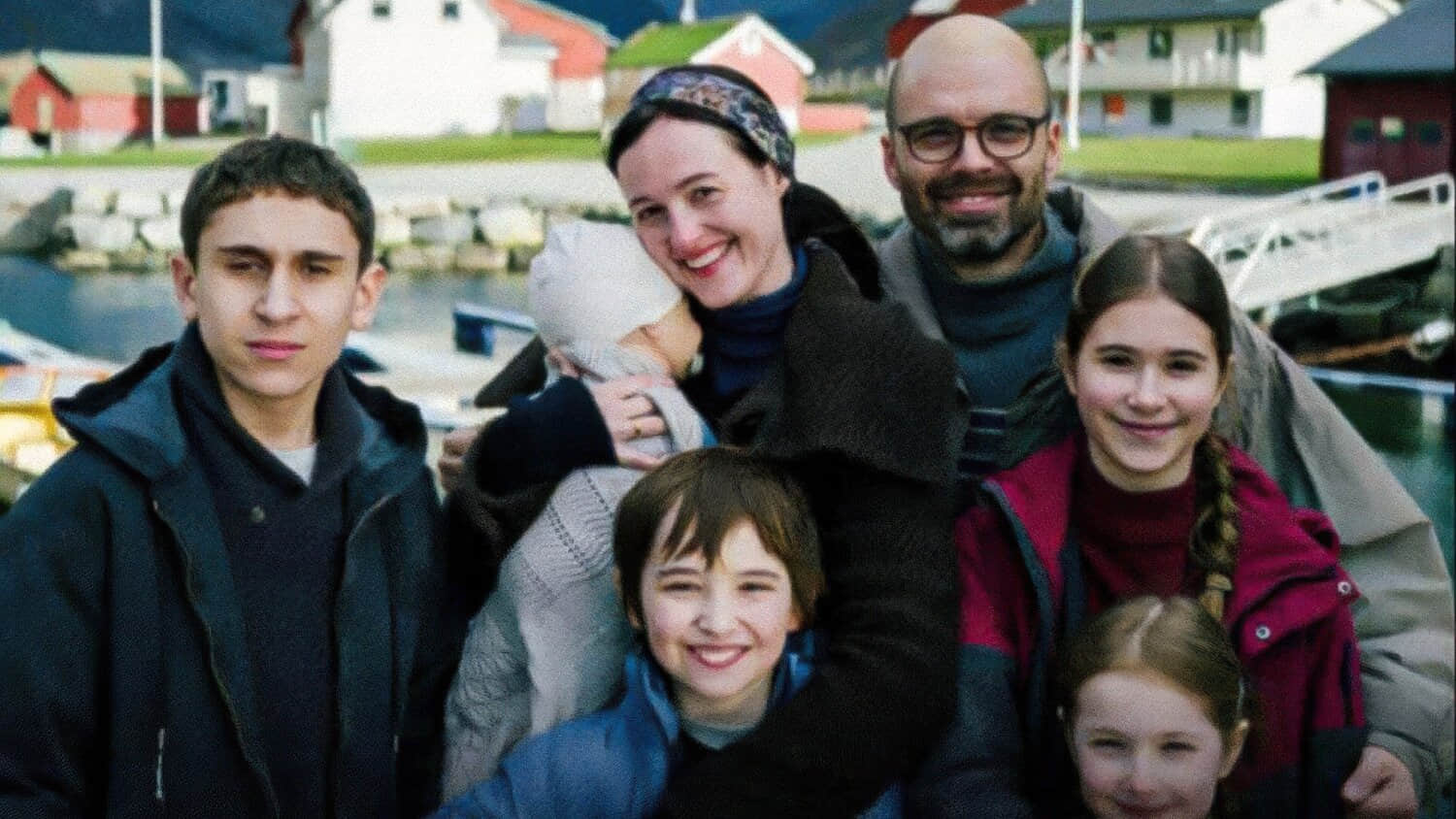 the-gheorghiu-family-posing-together-and-smiling-against-a-norwegian-village-background.jpeg