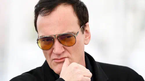 assets/quentin-tarantino-peers-forward-intently-while-attending-an-event.jpeg