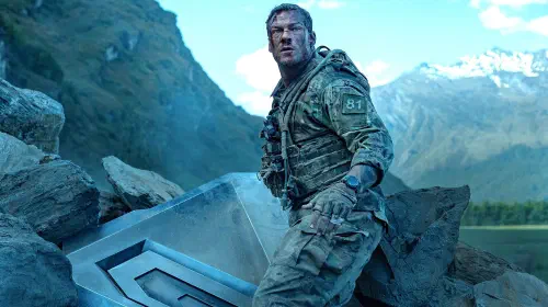 assets/alan-ritchson-s-81-standing-next-to-part-of-the-destroyed-machine-and-looking-beat-up-in-war-machine.jpeg