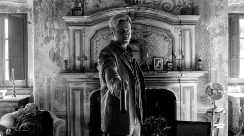 assets/gerard-butler-points-a-gun-at-oscar-isaac-sitting-on-a-couch-in-in-the-hand-of-dante.jpeg
