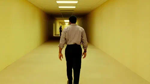 assets/chiwetel-ejiofor-as-clark-walking-down-a-hallway-toward-a-shadowy-figure-in-backrooms.jpeg
