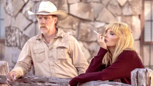 assets/kelly-reilly-s-beth-smoking-and-leaning-against-a-fence-next-to-marc-menchaca-s-zachariah-in-dutton-ranch.jpeg