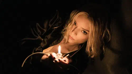 assets/anya-taylor-joy-leans-over-into-the-light-from-a-flame-on-a-lighter-in-apple-tv-series-lucky.jpeg