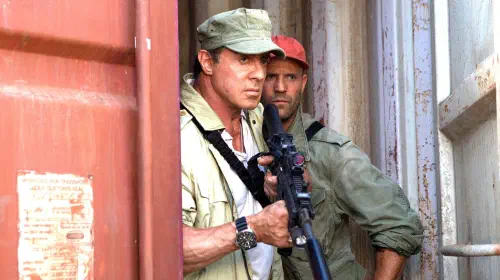 assets/sylvester-stallone-s-barney-holding-a-rifle-and-jason-statham-s-lee-standing-behind-him-looking-intense-in-the-expendables-3.jpeg
