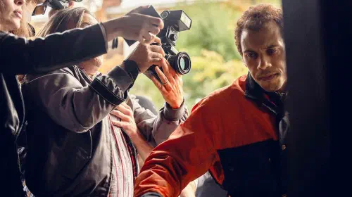 assets/a-man-avoiding-the-rush-of-cameras-in-the-witness.jpeg
