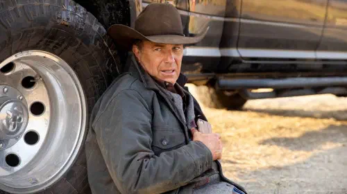 assets/john-dutton-kevin-costner-sitting-on-the-ground-leaning-against-a-truck-in-yellowstone-season-3.jpeg