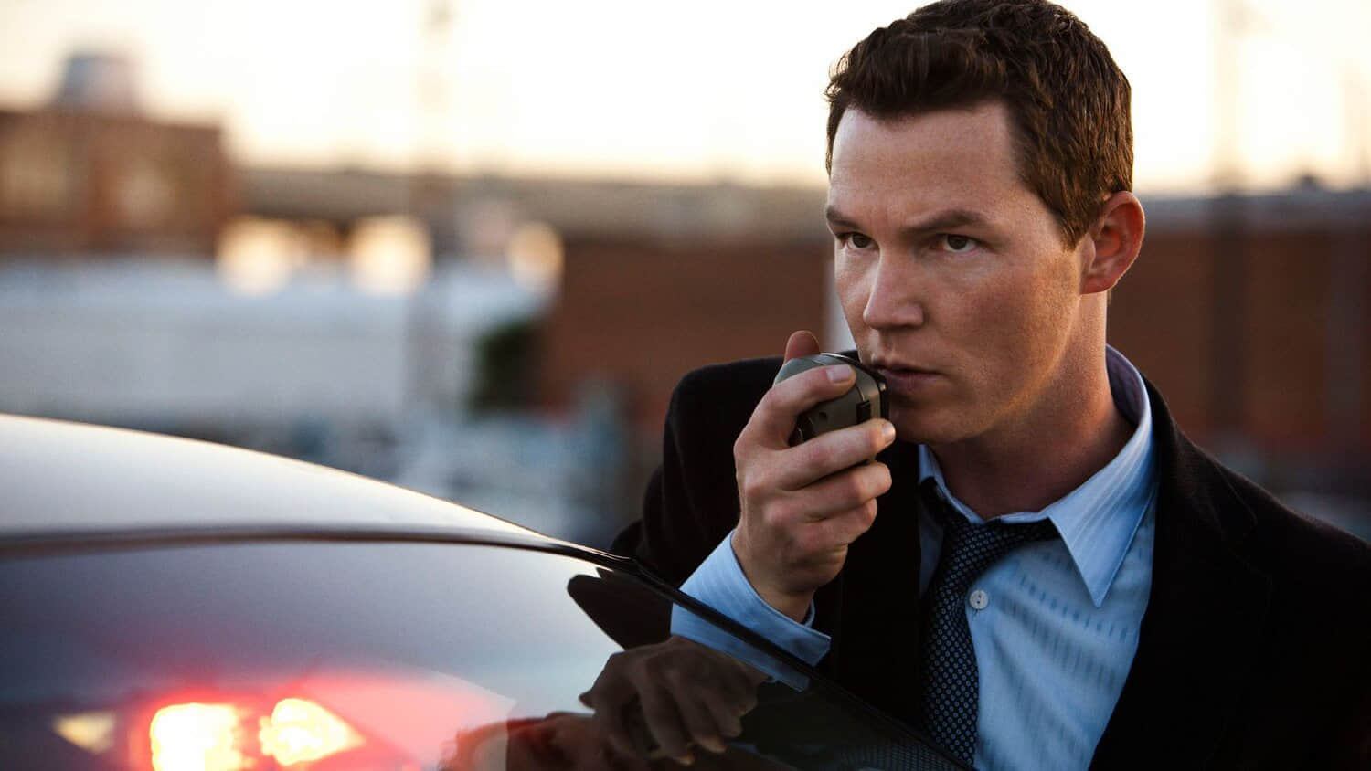 shawn-hatosy-speaking-into-a-walkie-while-standing-outside-of-his-police-car-in-southland.jpeg