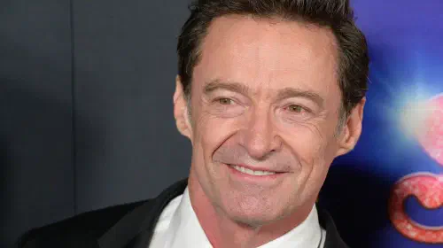 assets/hugh-jackman-smiling-for-a-photo-on-the-song-sung-blue-red-carpet.jpeg