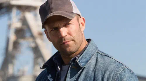 assets/jason-statham-wearing-a-denim-jacket-and-baseball-hat-in-the-film-homefront.jpeg