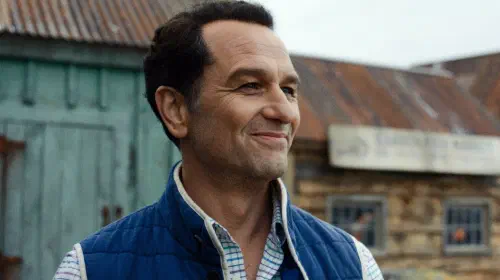 assets/matthew-rhys-as-tom-loftis-smiling-in-widow-s-bay-season-1.jpeg