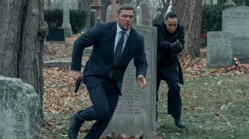 assets/alan-ritchson-and-maria-sten-run-through-a-graveyard-in-reacher.jpeg