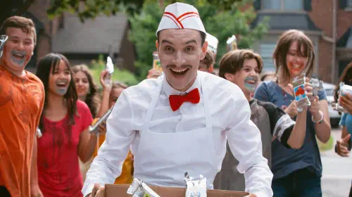 assets/the-ice-cream-man-smiling-as-kids-celebrate-behind-him.jpeg