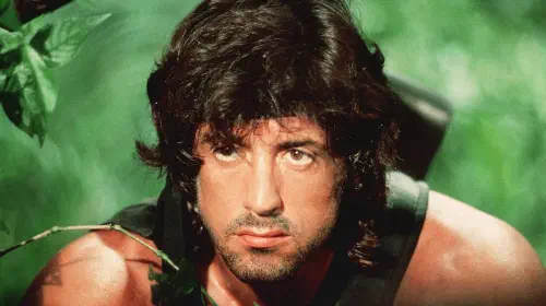assets/close-up-of-sylvester-stallone-as-rambo-as-he-peers-through-foliage.jpeg