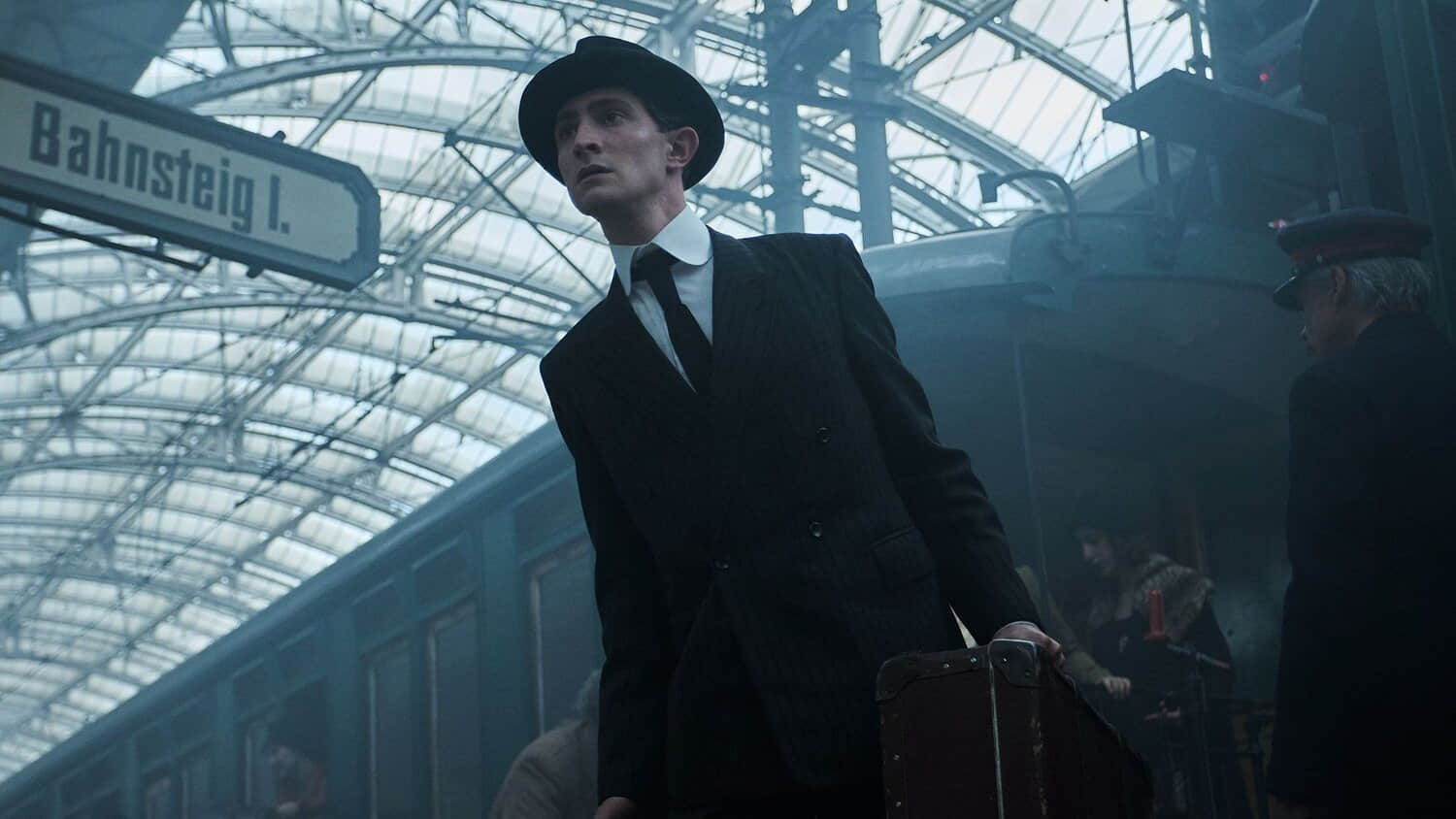 kafka-in-a-suit-and-hat-leaning-out-from-a-crowd-in-franz.jpeg