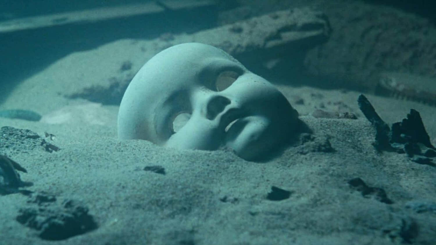 a-doll-mask-half-buried-in-the-sand-in-the-film-titanic.jpeg