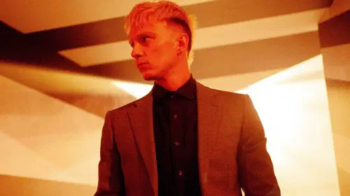 assets/drew-starkey-looking-to-his-right-in-a-warmly-lit-room-in-onslaught.jpeg